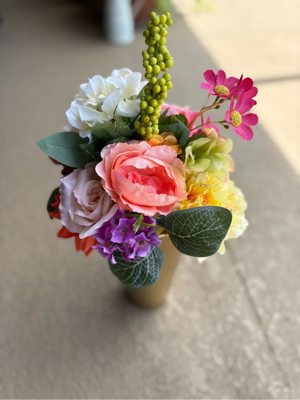 Floral arrangement features vibrant artificial flowers, including pink coral